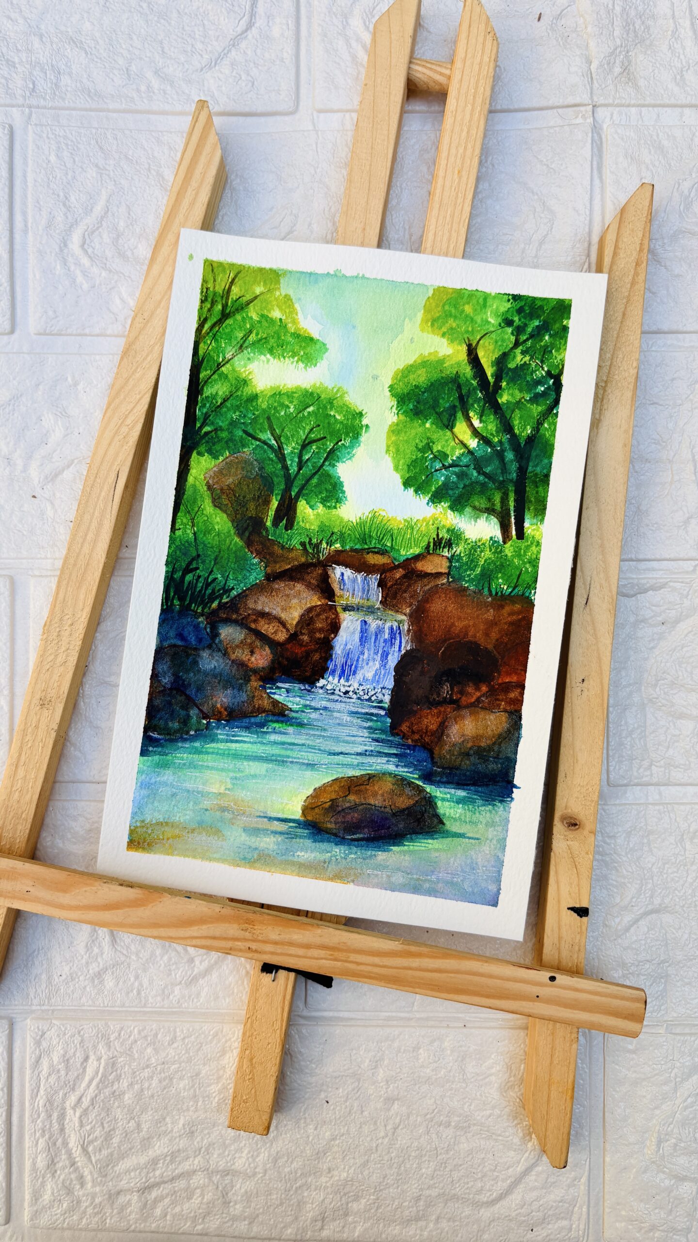 Forest Waterfall Escape Watercolor painting of a small waterfall in a green forest with rocks and flowing water